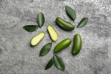 Photo of Fresh seedless avocados with green leaves on grey table, flat lay