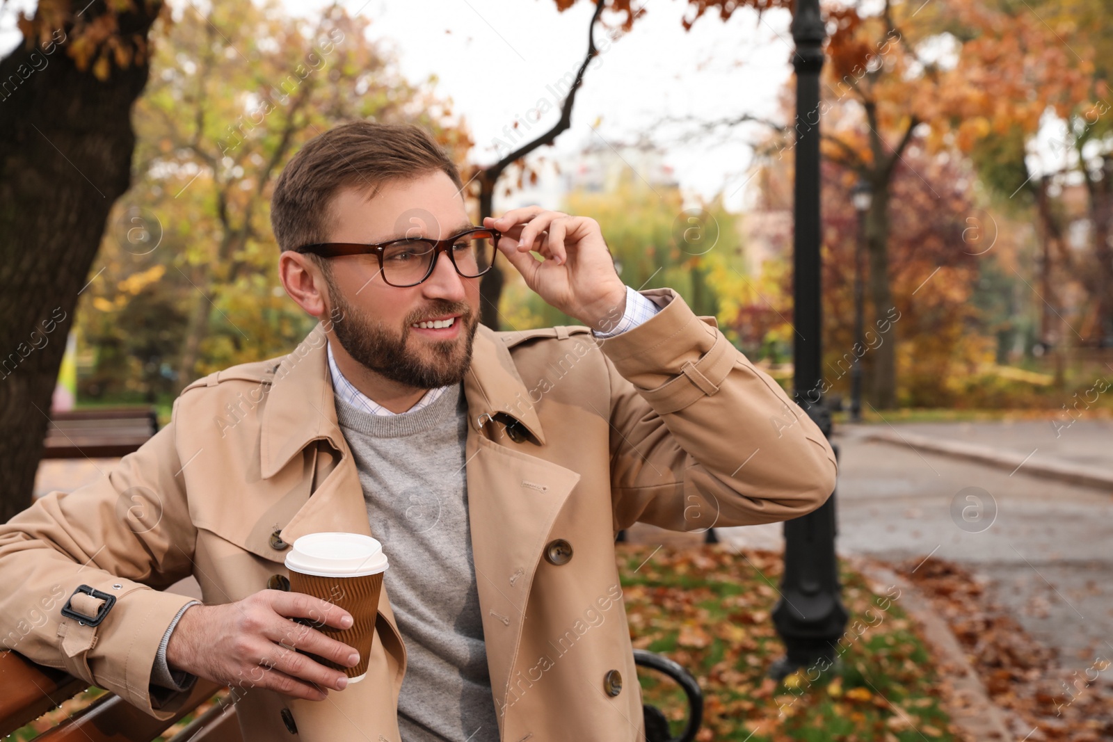 Photo of Handsome man wearing stylish clothes with cup of coffee in autumn park