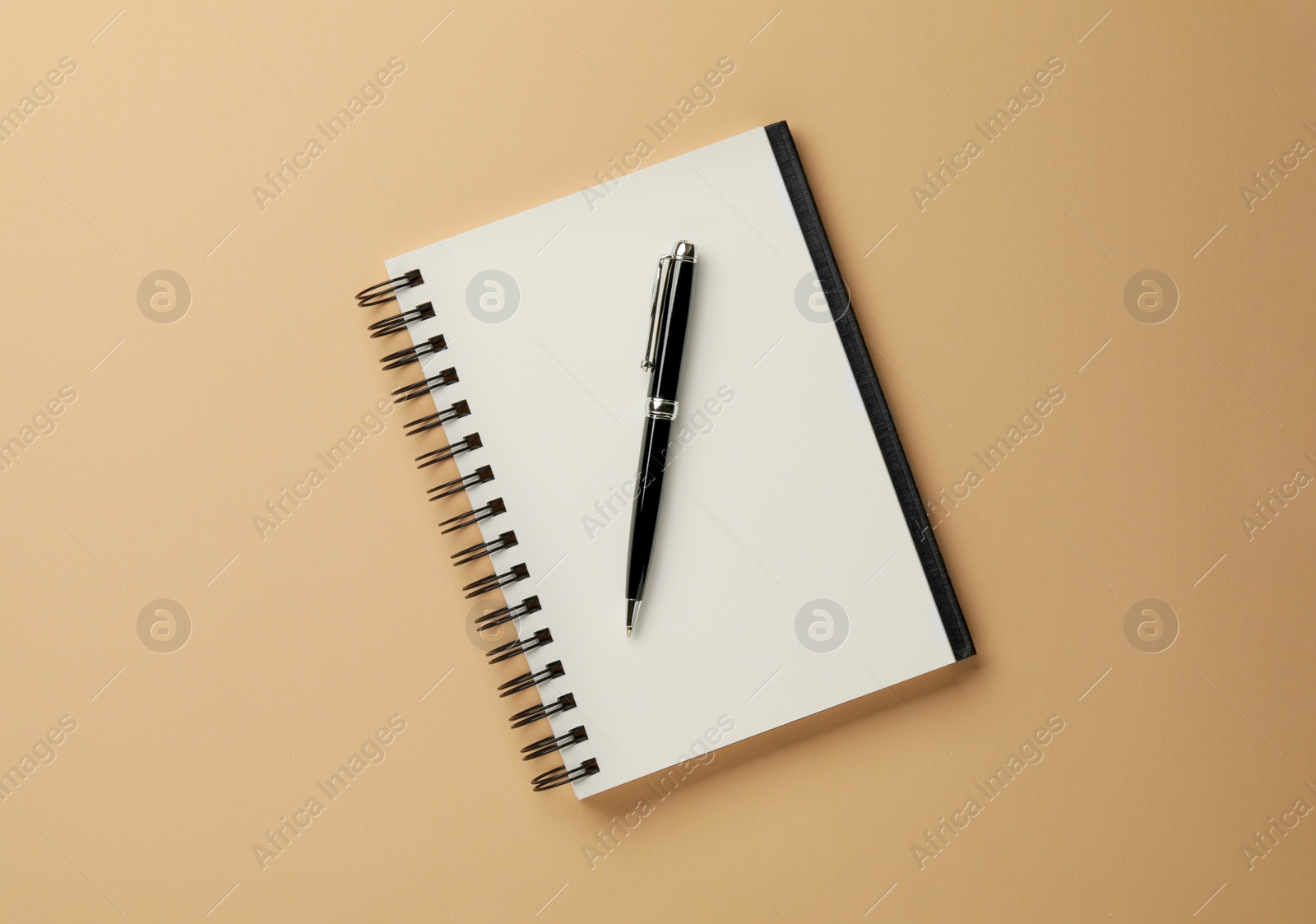 Photo of Notebook and pen on beige background, top view