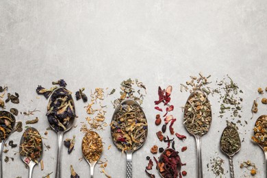 Flat lay composition with different dry teas and spoons on light table. Space for text