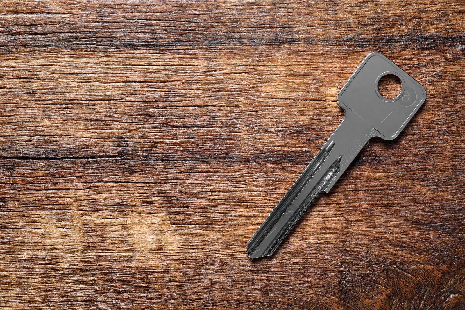 Photo of One key on wooden table, top view. Space for text