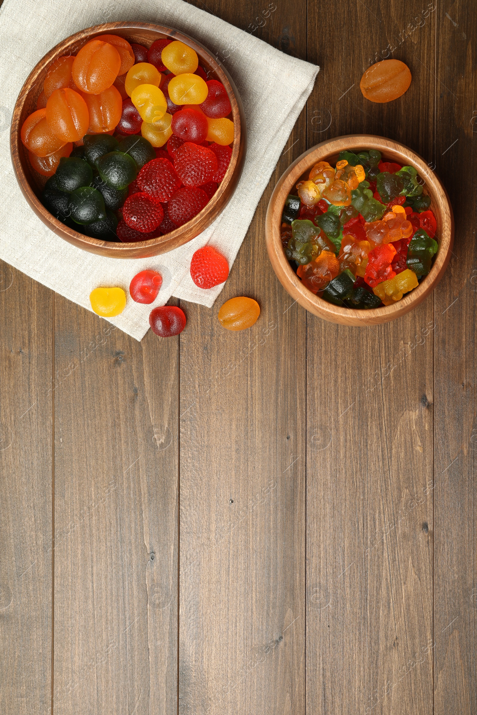 Photo of Delicious gummy candies on wooden table, flat lay. Space for text