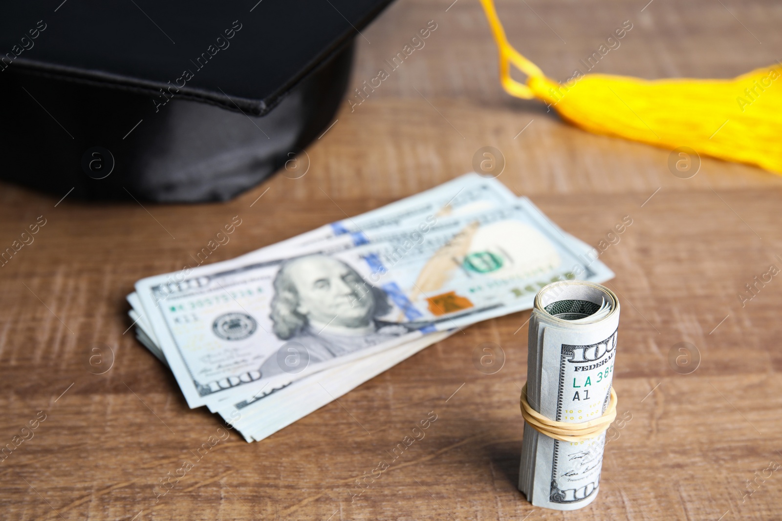 Photo of Dollar banknotes and student graduation hat on wooden background. Tuition fees concept