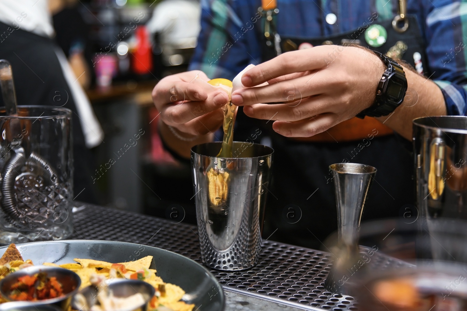 Photo of Bartender preparing tasty cocktail at counter in nightclub, closeup