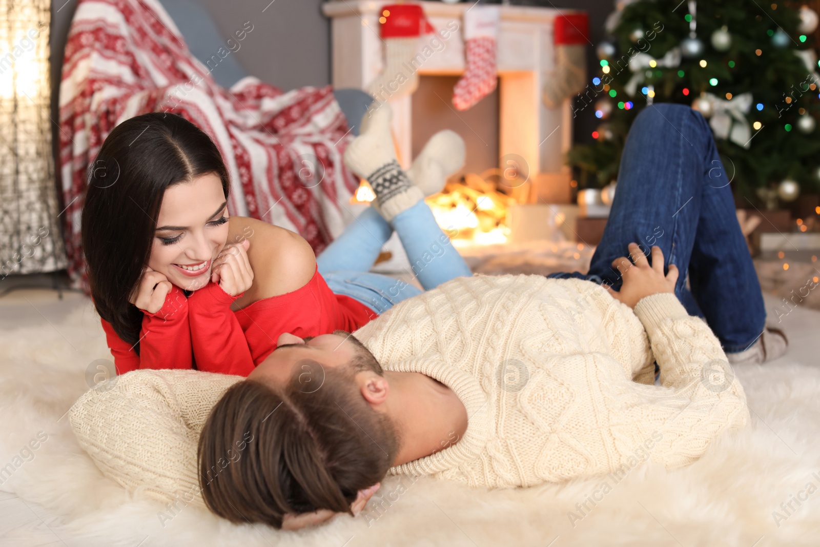 Photo of Happy young couple lying on floor at home. Christmas celebration