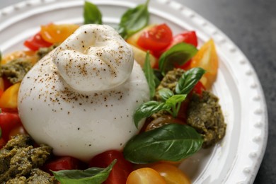 Delicious burrata salad with tomatoes, basil and pesto on plate, closeup