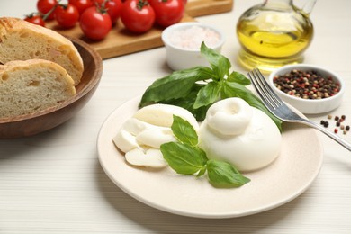 Photo of Delicious burrata cheese with basil served on white wooden table