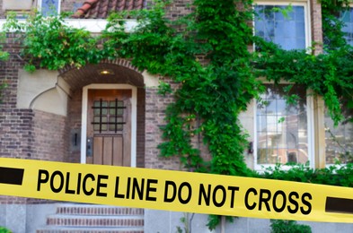 Image of Yellow crime scene tape blocking way to house outdoors