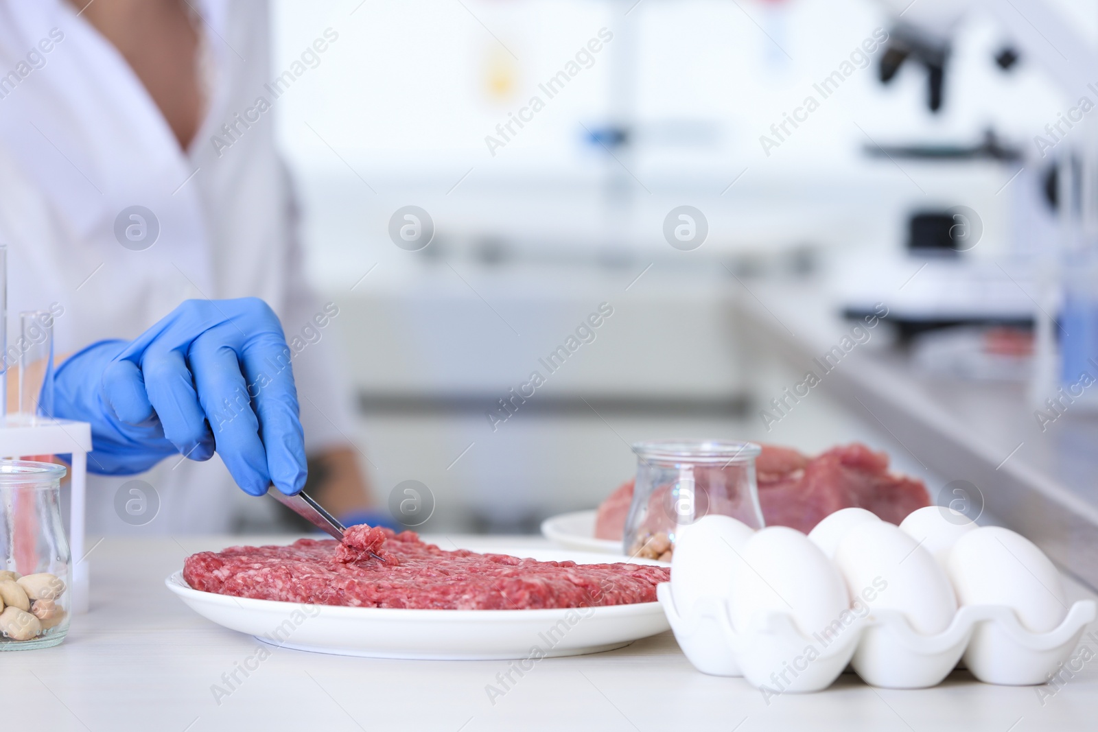 Photo of Scientist inspecting forcemeat at table in laboratory, closeup. Food quality control
