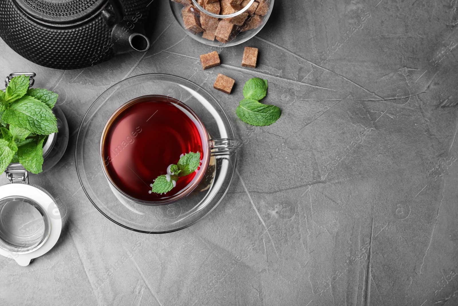 Photo of Fresh tea with mint and brown sugar on grey table, flat lay. Space for text