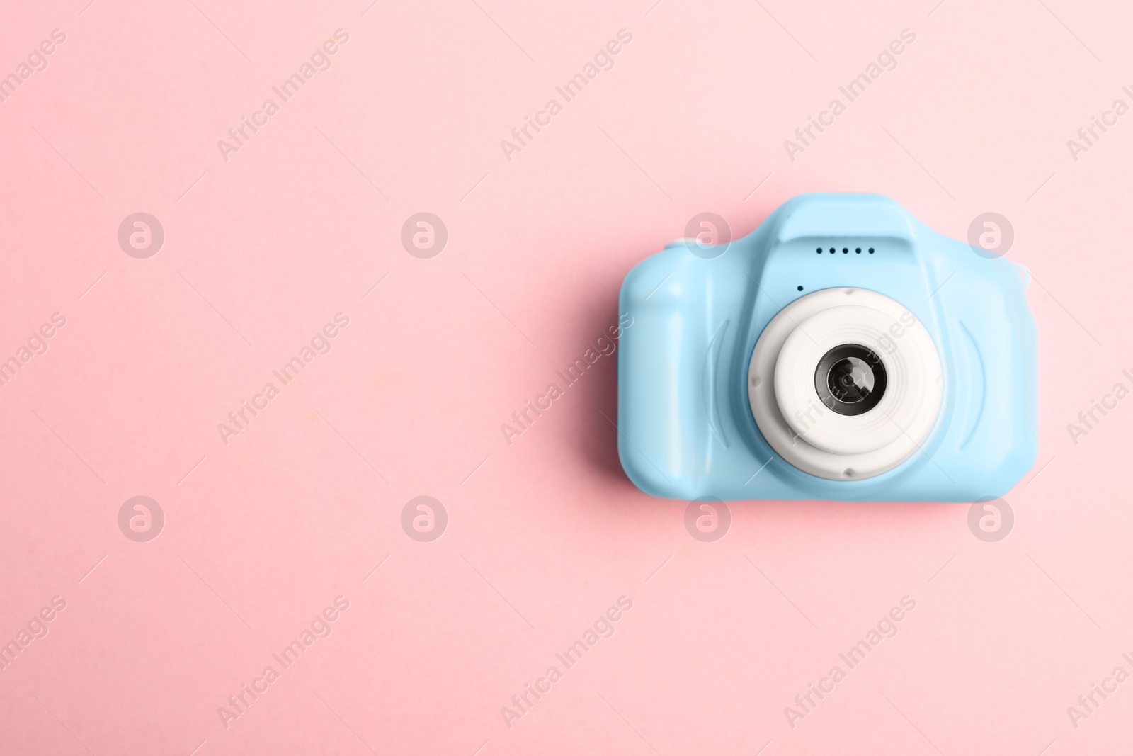 Photo of Light blue toy camera on pink background, top view with space for text. Future photographer