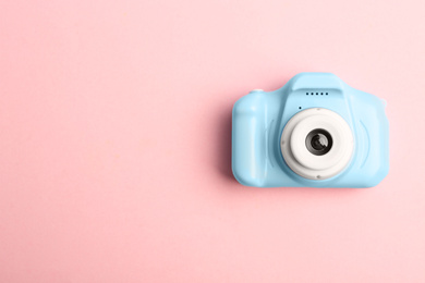 Photo of Light blue toy camera on pink background, top view with space for text. Future photographer