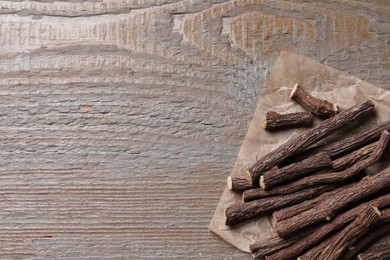 Photo of Dried sticks of liquorice root on wooden table, top view. Space for text