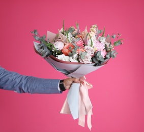 Photo of Man holding beautiful flower bouquet on pink background, closeup. Space for text
