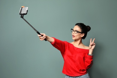 Photo of Attractive young woman taking selfie on grey background