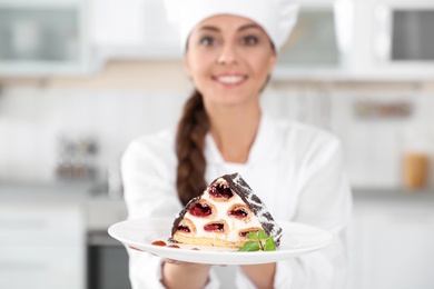 Professional female chef with plate of delicious dessert in kitchen