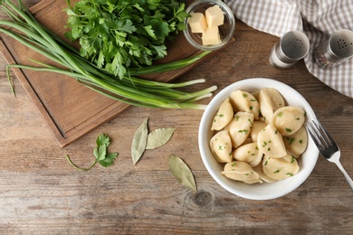 Photo of Delicious cooked dumplings with herbs on wooden table, flat lay