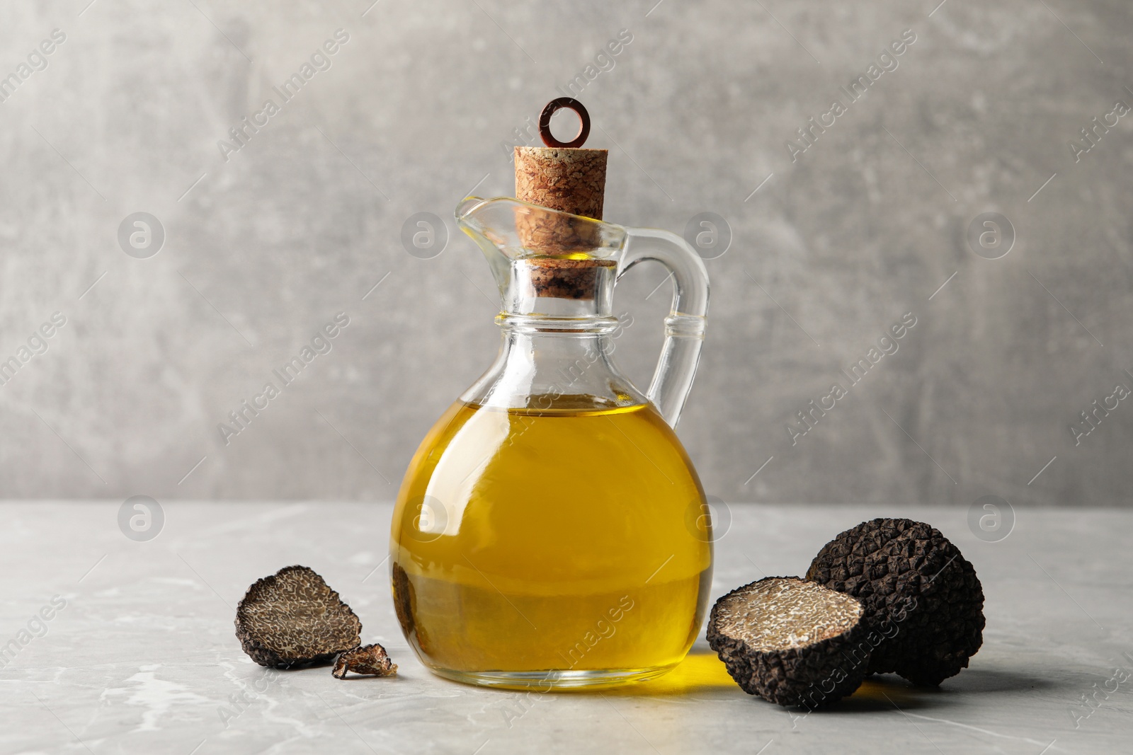 Photo of Fresh truffles and oil on light grey marble table