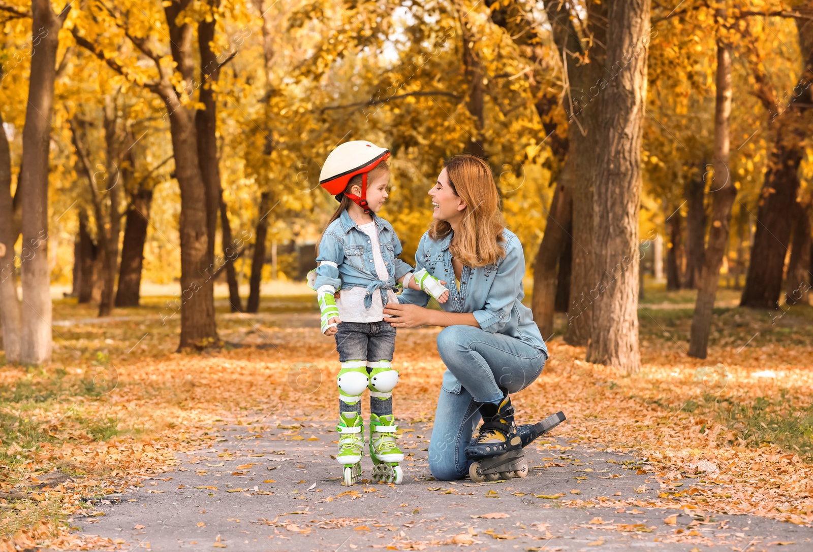 Photo of Mother and her daughter wearing roller skates in autumn park