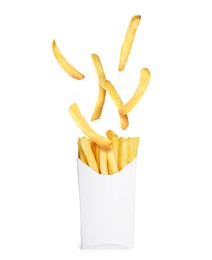 Tasty French fries falling into paper takeaway container on white background