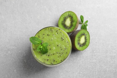 Photo of Delicious kiwi smoothie and fresh ingredients on light grey table, flat lay