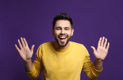 Photo of Young man laughing on purple background. Funny joke
