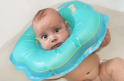 Cute little baby swimming with inflatable ring in bath