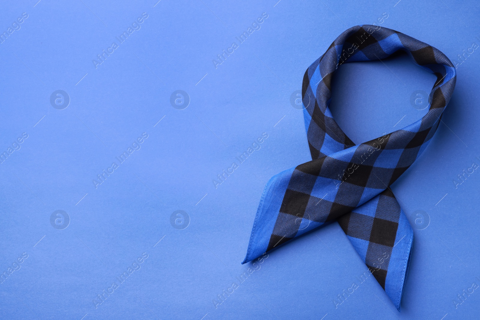 Photo of Folded bandana with check pattern on blue background, top view. Space for text