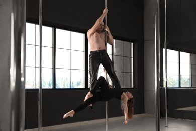 Photo of Young couple dancing in studio with poles