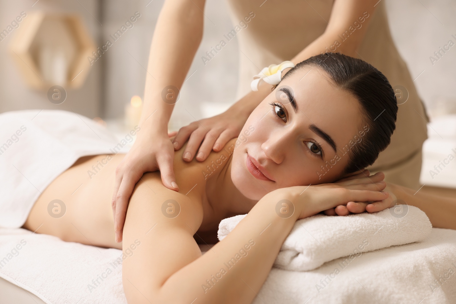 Photo of Woman receiving back massage on couch in spa salon