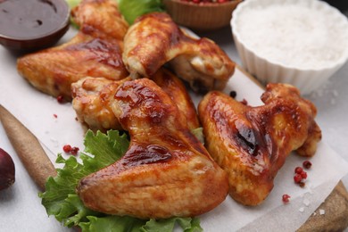 Photo of Fresh marinated chicken wings, spices and lettuce on light table, closeup