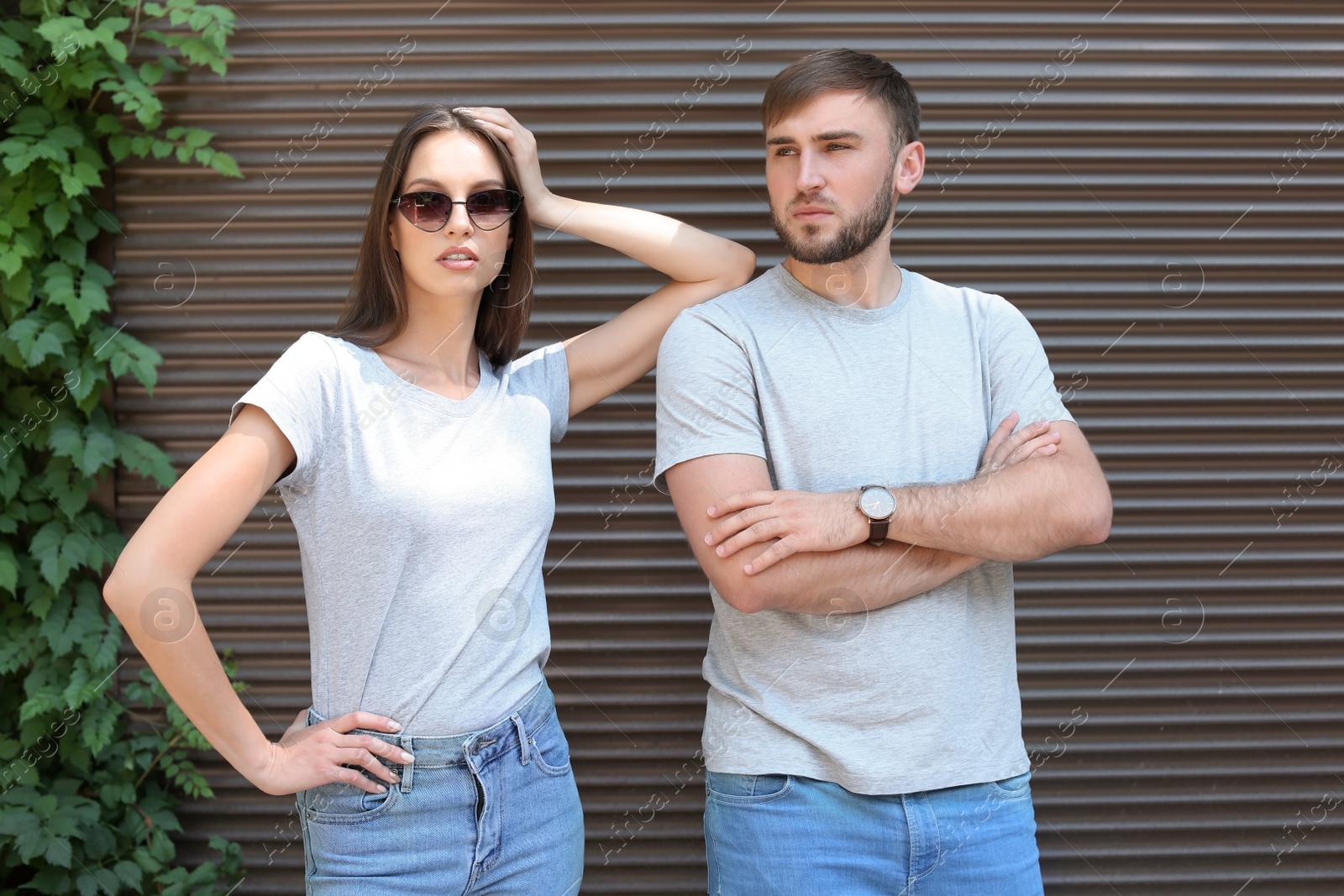 Photo of Young couple wearing gray t-shirts near wall on street.