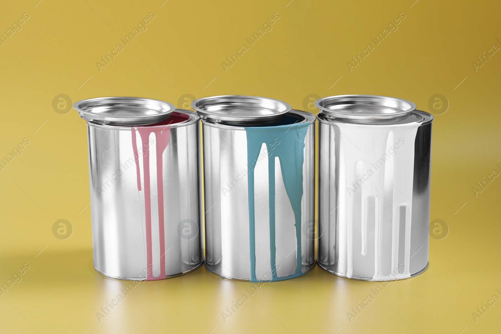 Photo of Cans of different paints on yellow background