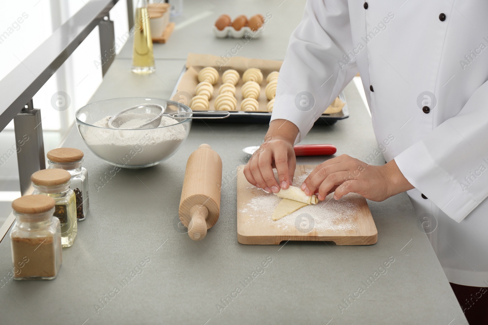 Photo of Female pastry chef preparing croissant at table in kitchen, closeup