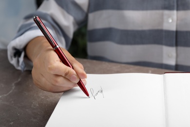 Photo of Writer signing autograph in book at table, closeup