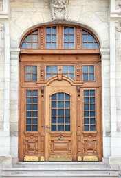 Entrance of house with beautiful arched wooden door, elegant molding and transom window