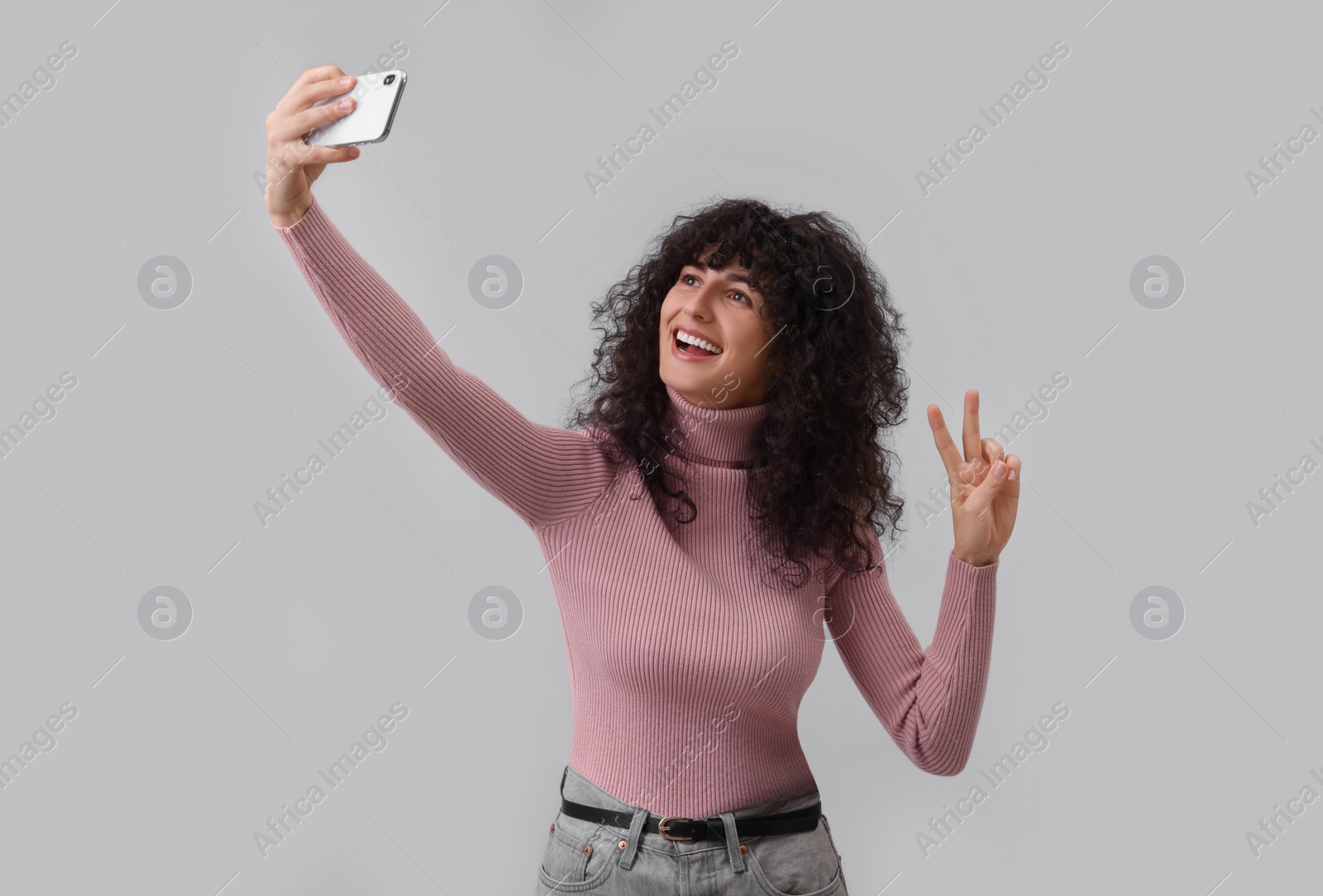 Photo of Beautiful young woman taking selfie on light grey background