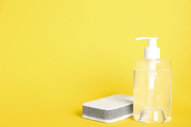Detergent and sponge on yellow background, space for text