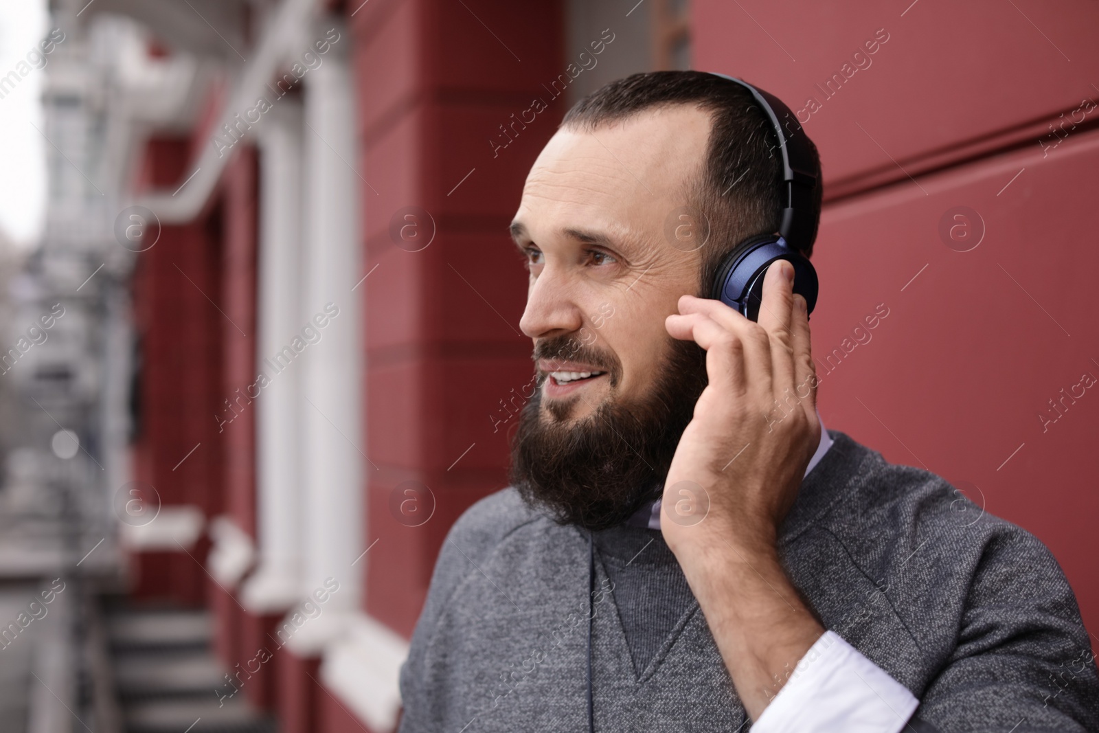 Photo of Mature man with headphones listening to music outdoors. Space for text