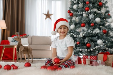 Photo of Cute little girl with box of Christmas balls at home