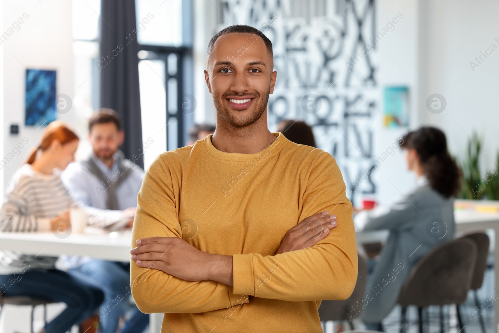 Photo of Team of employees working together in office. Happy man indoors