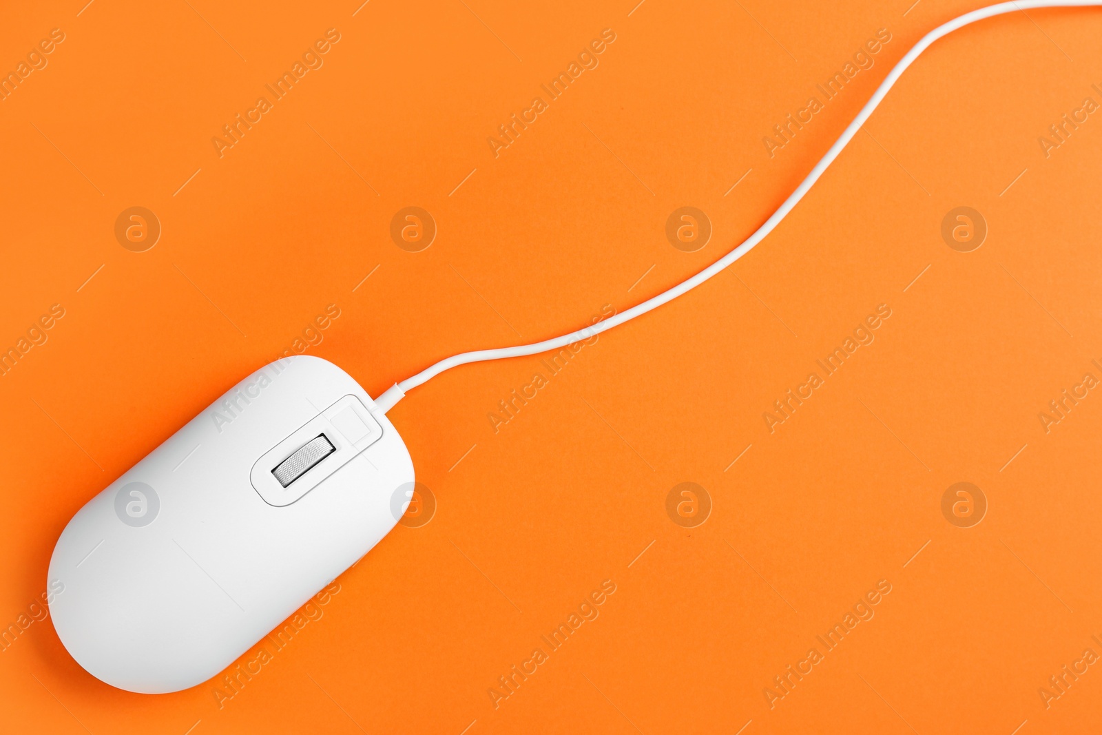 Photo of Modern wired optical mouse on orange background, top view