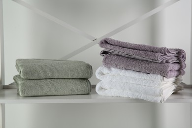 Stacks of soft towels on shelf indoors