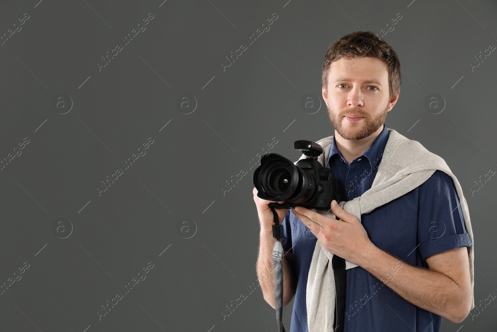 Photo of Man with camera and space for text on gray background. Professional photo studio