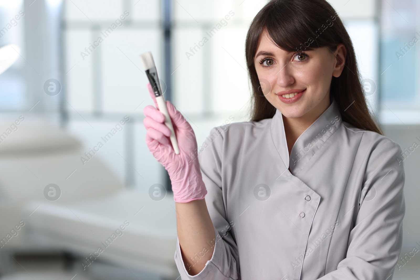 Photo of Cosmetologist with cosmetic brush in clinic, space for text