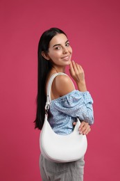 Photo of Fashionable young woman with stylish bag on pink background