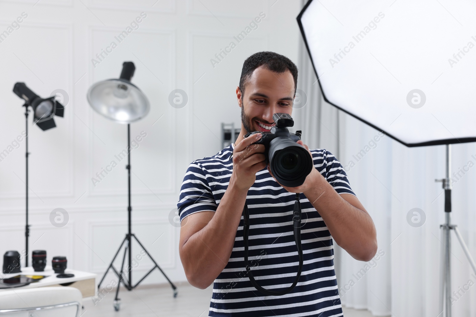 Photo of Young professional photographer with camera in modern photo studio, space for text