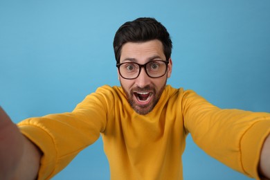 Photo of Happy man taking selfie on light blue background