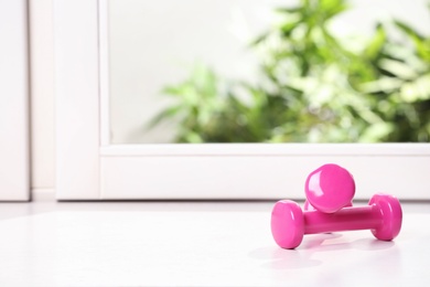 Photo of Vinyl dumbbells on windowsill, space for text