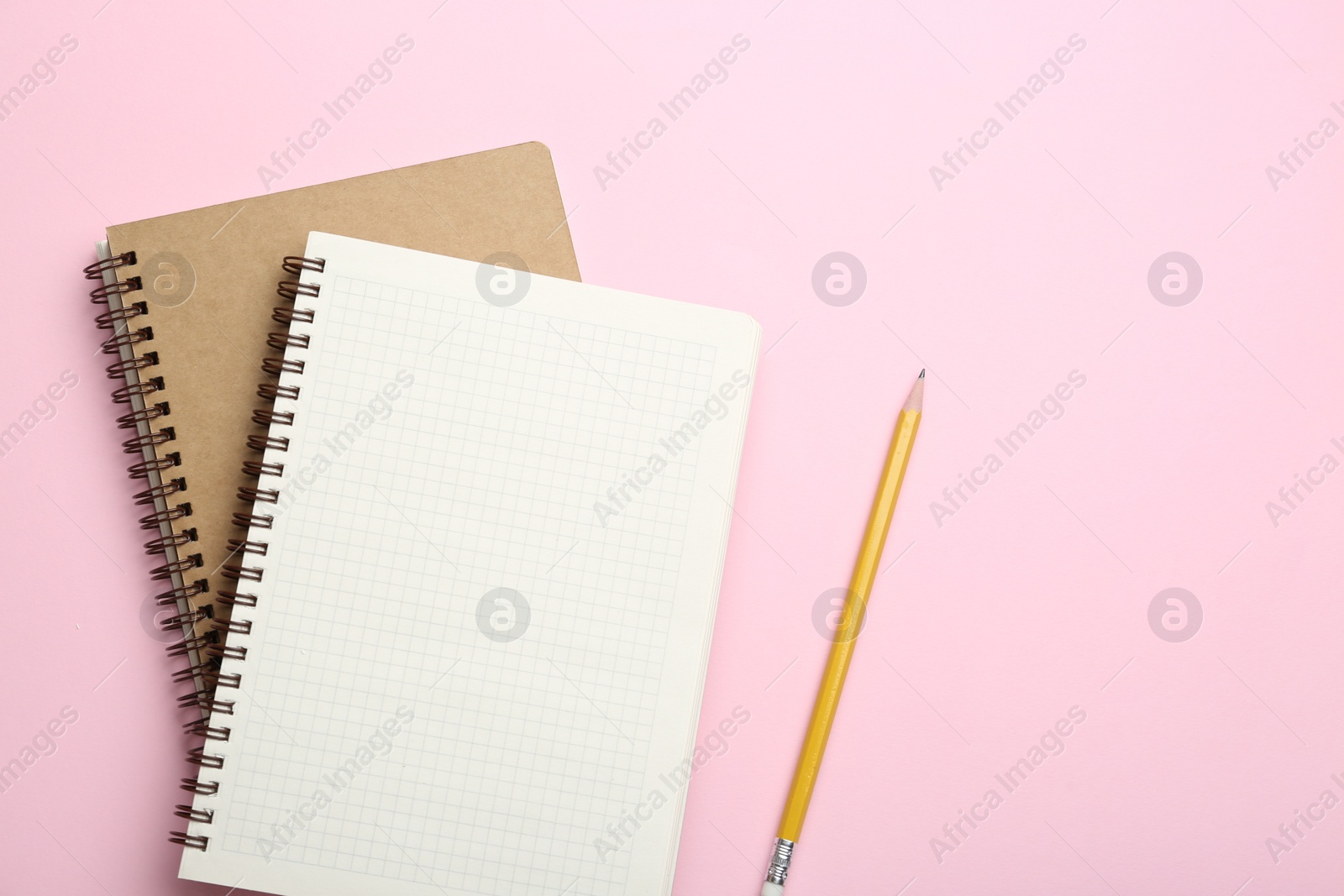 Photo of Notebooks and pencil on pink background, top view. Space for text